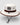 beige wide brim bucket hat with brown band and chin strap, logo patch on front