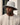 Castelli bucket hat with a wide brim and chin strap, light grey, worn by man in a beige sweatshirt against an urban backdrop.