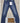 blue denim jeans with a white tag attached at the front waistband, displayed on a light wood background
