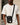 man wearing a white t shirt with a compact black sling bag across his body, front flap pocket and small logo patch