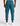 back view of teal track pants with a zippered back pocket and side cargo pockets, cuffed ankles, paired with white sneakers