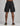 back view of black cargo shorts with side pockets on both thighs and an elastic waistband, paired with black sneakers with
