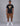 man in a black short sleeve graphic tee with orange emblem and white lettering, brown cargo shorts, white sneakers