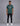 man wearing a green short sleeve t shirt with a white graphic logo on the chest, black jeans, white sneakers, and a plain