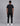 back view of a man wearing a black short sleeve t shirt and black cargo pants with white sneakers in a studio background