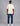 man seen from the back wearing a cream short sleeve tee shirt, blue denim jeans, and white sneakers